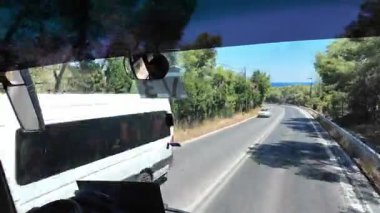 Kırsal yolda, otobüsün ön camından, yaklaşan arabaların görüntüsü. Kos. Yunanistan. 