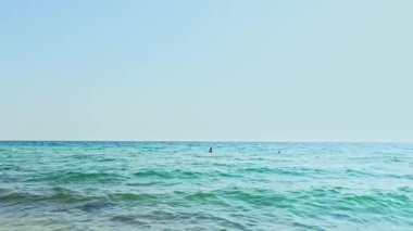 Ege Denizi 'nin dalgaları kumlu sahile ulaşıyor güneş şemsiyeleri ve kıyıda turistlerle. Rodos. Yunanistan. 