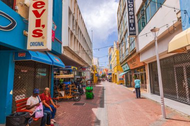 Willemstad 'daki yayalar, bulutlu gökyüzünün arka planındaki banklarda insanlar..