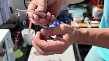 Yakından bakıldığında, elinde taze yapılmış bok eziciler, ellerinde plastik balık yemi tutan bir adam görülüyor.. 