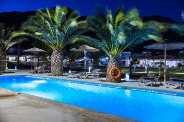 Otelde geceleri palmiye ağaçları olan güzel bir yüzme havuzu manzarası. Yunanistan. Kos. 