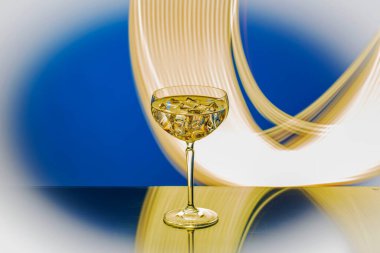 Soyut ışık ile yansıtıcı yüzeyde duran içecek ve buz dolu zarif camların yakın görüntüsü.