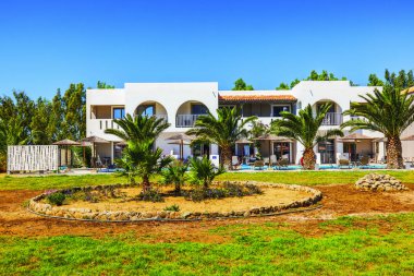 Balkonları, palmiye ağaçları ve açık mavi gökyüzü arka planında güneş panelleri olan güzel bir otel manzarası. Kos. Yunanistan. 