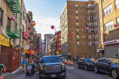 Street in Chinatown decorated with colorful lanterns cars parked along buildings with Chinese shop signs. New York. USA. 