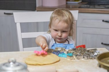 Sevimli sarışın küçük çocuk ev mutfağında hamuru kesiyor. Yatay olarak. 
