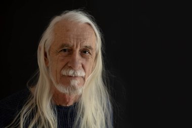 Uzun beyaz saçlı, gülümseyen, çekici bir ihtiyarın stüdyo portresi. Yatay olarak. 