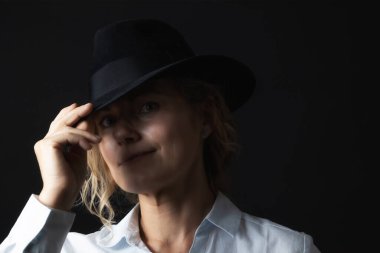 Gülümseyen orta yaşlı siyah şapkalı bir kadının sade portresi.. 