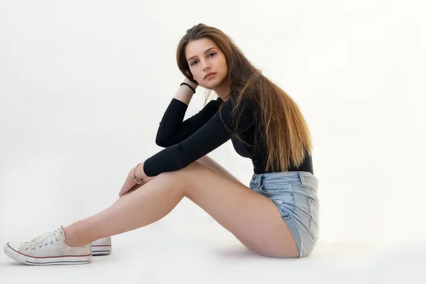 Uzun Bacaklı Genç Kız Işık Arka Planında Yerde Oturuyor Kız — Stok fotoğraf