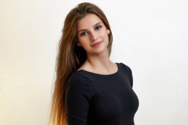 Uzun saçlı çekici kız arka plandaki kameraya gülümsüyor. Yatay olarak. 