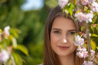 Çekici esmer kız kiraz filizlerinin yanında poz veriyor. Yatay olarak. 