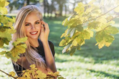 Gülümseyen, uzun saçlı, açık havada poz veren bir kızın portresi.. 