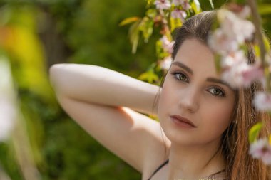 Havalı esmer kız açık havada, Sakura ağacının yakınında poz veriyor. Yatay olarak. 