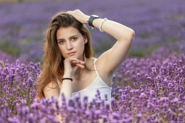 Uzun saçlı, esmer, düşünceli kız lavanta tarlasında poz veriyor. Yatay olarak. 