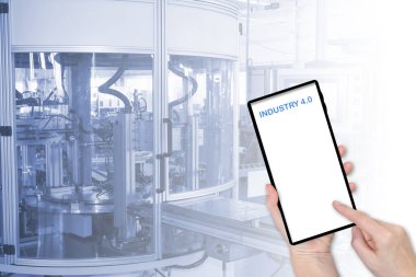 Sanayi 4.0 konsepti. Finger akıllı telefondan boş ekrana dokunuyor. Mesajınız için hazır. Arka plandaki üretim hattının kasıtlı olarak bulanık görüntüsü. Tüm potansiyel markalar kaldırıldı