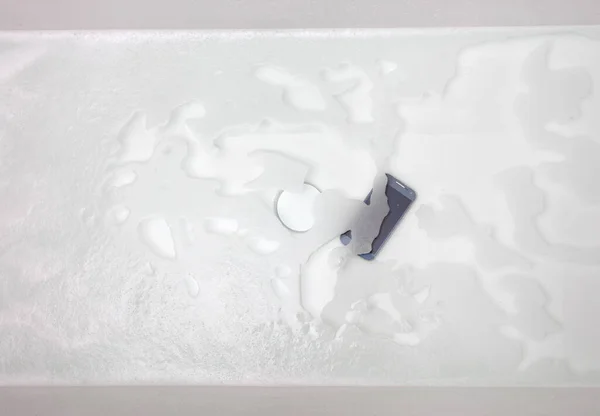 黑色的智能手机躺在水里 在浴缸里掉下去 — 图库照片