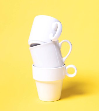 Katı sarı arka planda izole edilmiş beyaz kahve fincanları.