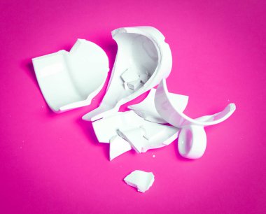 Kırık bardak pembe bir arka planda izole edilmiş.