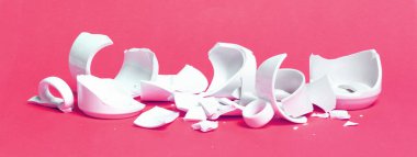 Kırık bardak pembe bir arka planda izole edilmiş.