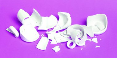 Kırık bardak pembe bir arka planda izole edilmiş.