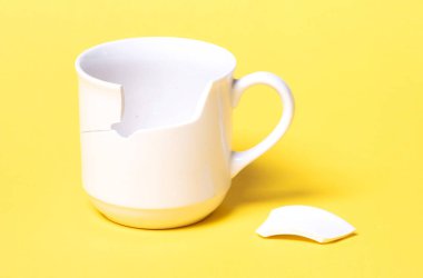 Kırık bardak sarı bir zeminde izole edilmiş.