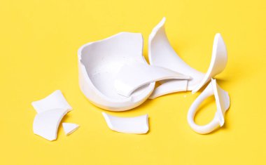 Kırık bardak sarı bir zeminde izole edilmiş.