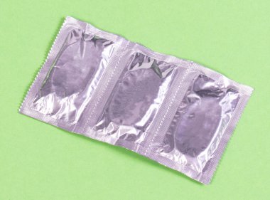 Yeşil arka planda izole edilmiş prezervatifler