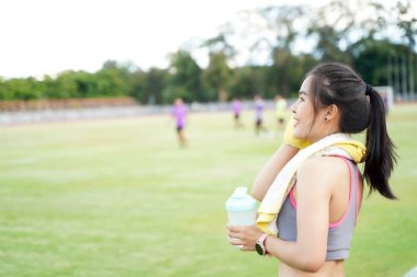 Genç bayan antrenmandan sonra dinleniyor ve sabahları futbol stadyumunda koşuyor.