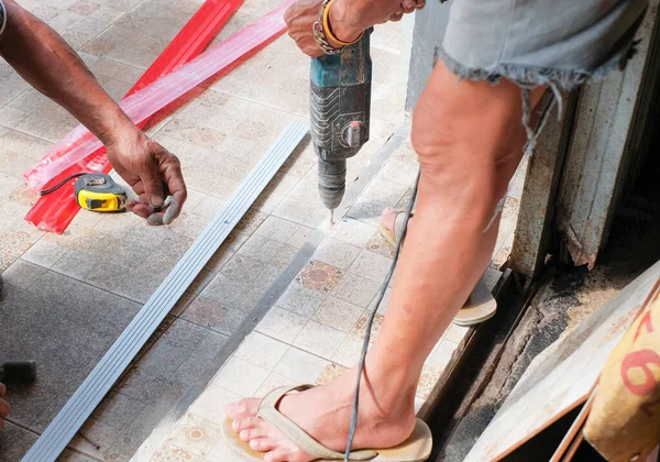 stock image Closeup hands of laborer holding electric drill working drilling aluminum lumber at construction site.