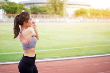 Genç bayan antrenmandan önce dışarıda ısınıyor ve güneş ışığıyla futbol stadyumunda koşuyor..