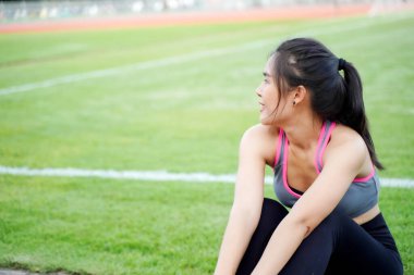 Genç bayan antrenmandan sonra dinleniyor ve sabahları futbol stadyumunda koşuyor.