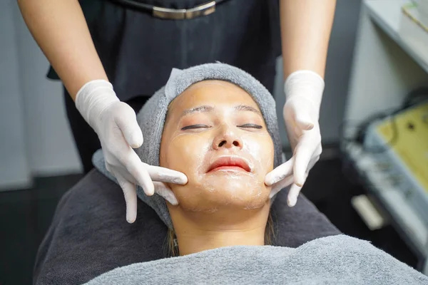 Closeup beauty woman making face spa and facial mask from cream to condition and treat the face in beauty clinic.