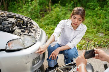 Closeup female accident victim points out the damaged area for the insurance officer to take a photo for insurance claim.