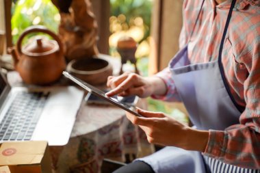 Closeup and crop vendors check and taking orders in her online shop.