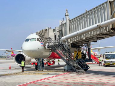 Bangkok, Tayland 16 Nisan 2022: Tayland uçağıyla Suvarnabhumi Uluslararası Havaalanı 'nın dış görüntüsü geldi ve parlayan mavi gökyüzü altında jet köprüsü ile yolcu getirdi..