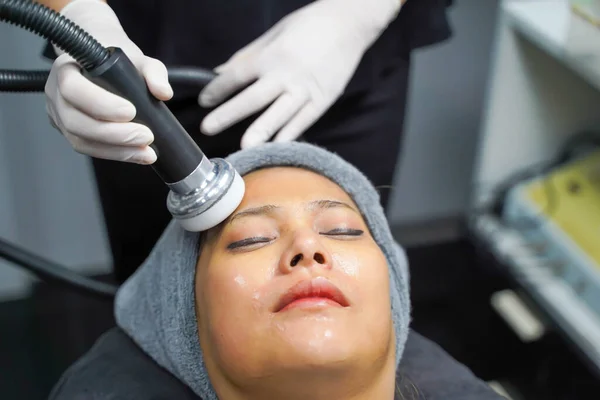 stock image Closeup Asian beauty woman having therapy to stimulate facial skin and facial ultrasonic skincare treatment by professional cosmetologist wellbeing.