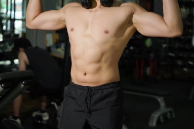 Spor salonunda ağırlık eğitimi almış mükemmel bir vücudu yakın çekim ve kırpma..