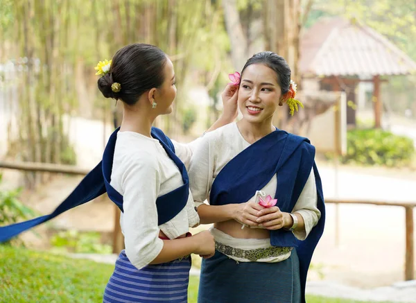 stock image Closeup a beautiful Thai young lady ware Thai northern traditional dress chatting and teasing each other on blurred background.