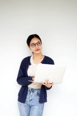 Kapanış mutluluğu, neşeli Asyalı genç kız öğrenci, günlük giysiler içinde ve beyaz gradyan arkaplanda dizüstü bilgisayar yazarken. Asya okulu kavramı.