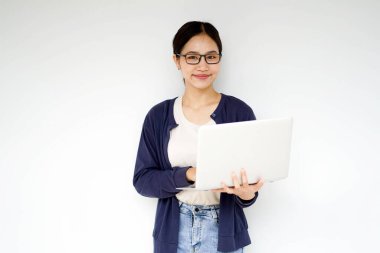 Giyim kuşamında ve beyaz bir arka planda dizüstü bilgisayar yazma eylemi içinde genç ve güzel bir kız öğrenci. Asya okulu kavramı.