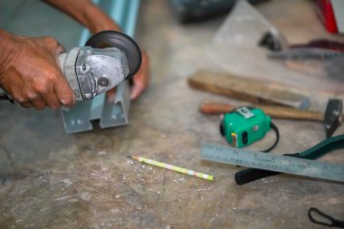 Ustanın yakın çekim elleri inşaat alanındaki alüminyum keresteyi keserken elektrikli değirmeni tutan metali gördü..