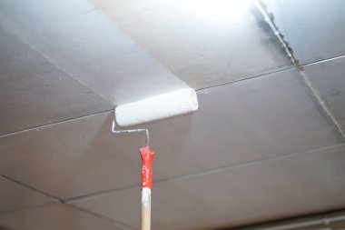 Yakın plan eski evin tadilatı için tavana boyanmış bir silindir..