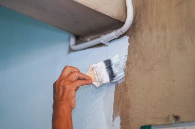 Ressamın eli bir boya fırçası tutuyor. Duvara beyaz renkler çiziyor. Eski evi yeniliyor..