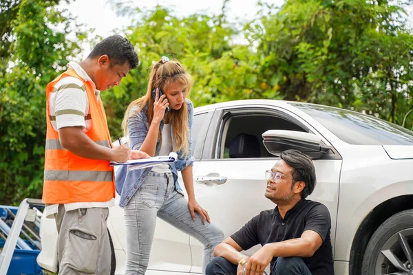 Insurance company officers post a list of repairs on work list clipboard with 2 driver agreed on damages related to car accidents on road side. Traffic accident insurance concept