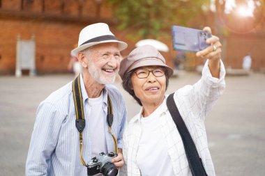 Tur rehberiyle yakın plan Amerikalı turist şehrin arka planında bulanık bir fotoğraf çekiyor. Kıdemli turist konsepti