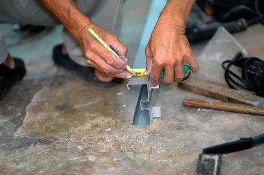 İnşaat alanındaki alüminyum keresteyi kesmeden önce, kalemi kullanarak yapıcının elleri detayları işaretler..