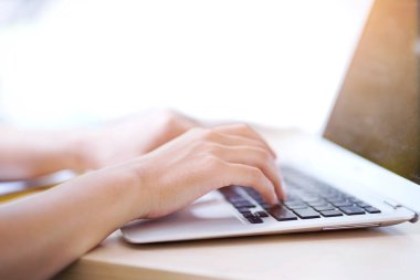 Yakın plan ve kesme elleri kullanan bir kadının elleri ve parlak arka planı olan bir dizüstü bilgisayar klavyesi..