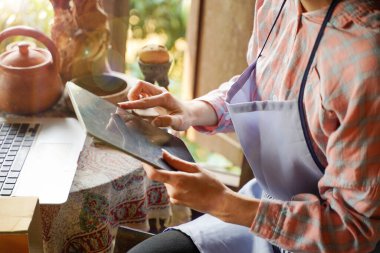 Ürün stoklarını ve siparişlerini kontrol etmek için bir tablet kullanan satıcılar..