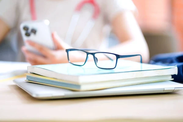 Closeup eyeglasses placed on top of textbooks on a medical student\'s desk and blurred of medical student relaxing background. Education concept