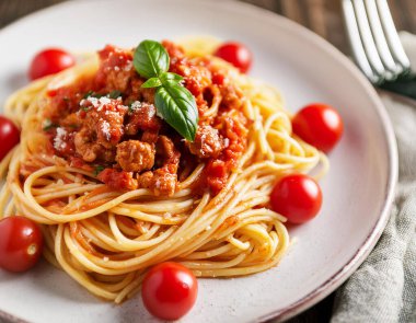 Domates soslu spagetti tabağı ve masada çatal ve kaşıkla kıyma.