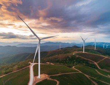 Yüksek açılı dağdaki yel değirmeni manzarası günbatımı ve bulutlu gökyüzü arkaplanı.